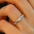 Woman's hand wearing minimal gold twist band ring with CZ stones