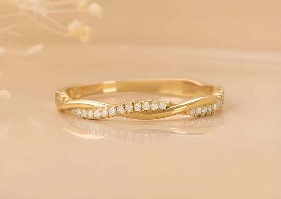 Woman's hand wearing minimal gold twist band ring with CZ stones